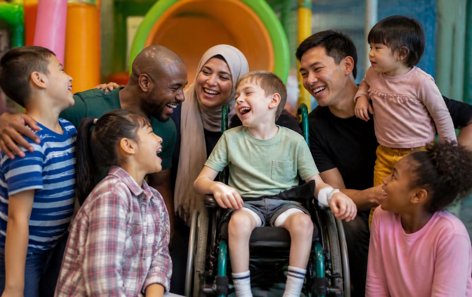 A diverse group of families and children of different ages and abilities laughing together