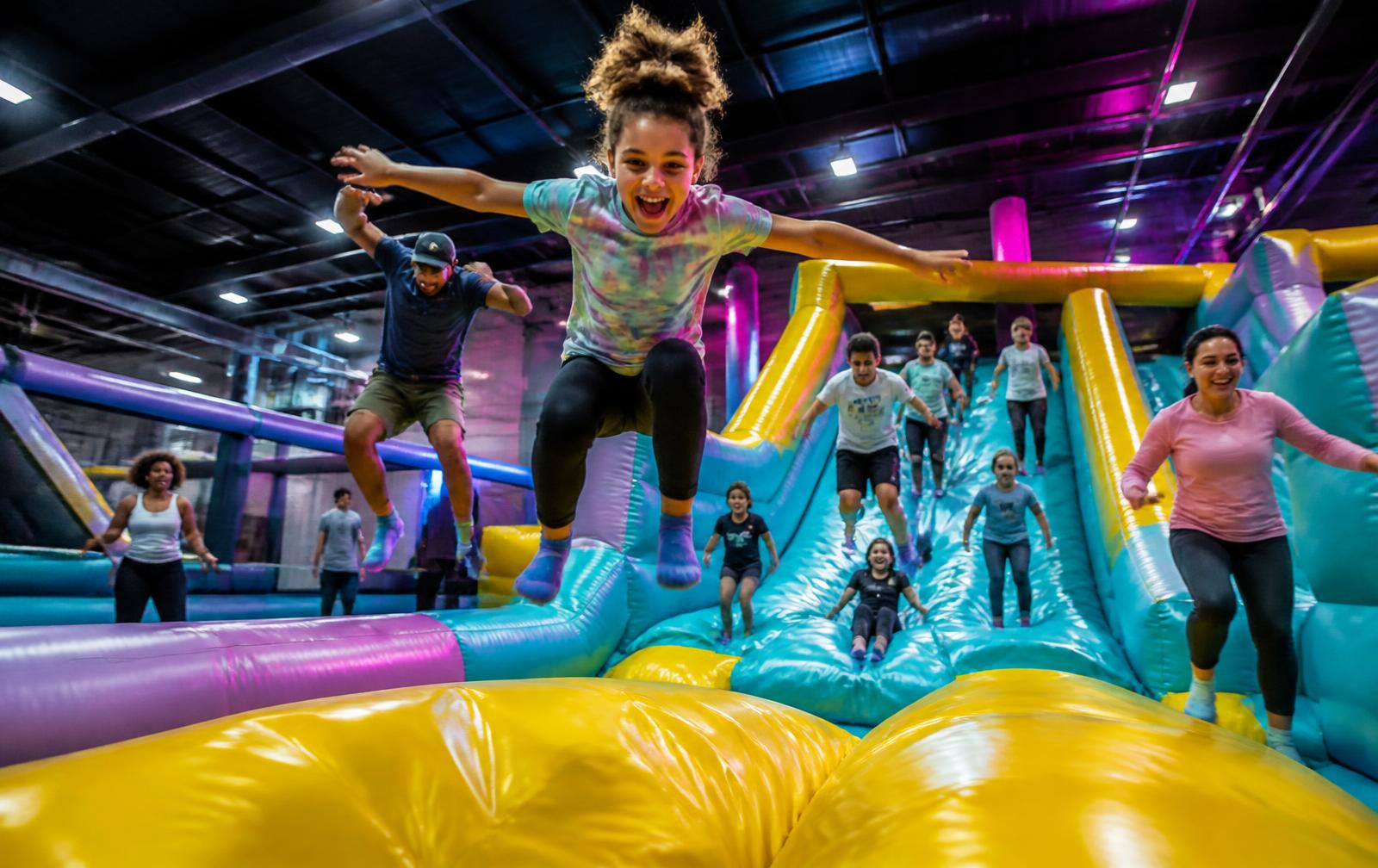 Children mid-jump on turquoise and yellow inflatables